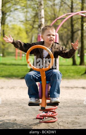 Junge auf Spielplatz Schaukeln. Stockfoto