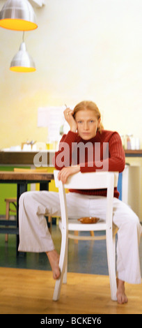 Junge Frau sitzt hinten auf dem Stuhl Rauchen Stockfoto