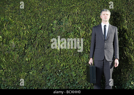 Geschäftsmann vor Hecke Stockfoto