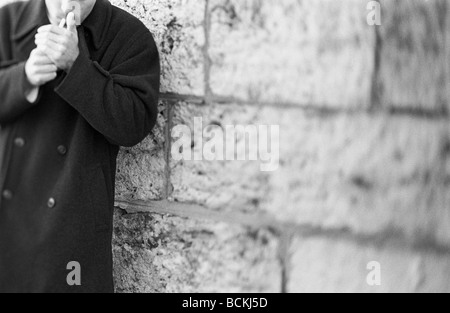 Mann Rauchen weiter an der Wand, Mittelteil, b&w Stockfoto