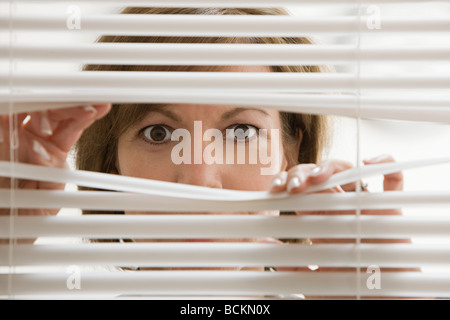 Geschäftsfrau sucht durch Jalousien Stockfoto