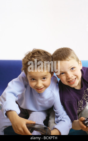 Zwei jungen auf Sofa mit Joysticks, Blick in die Kamera Stockfoto
