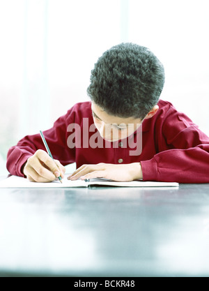 Junge schreiben an Tisch, Vorderansicht Stockfoto