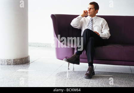 Geschäftsmann auf Sofa sitzen, mit Handy Stockfoto