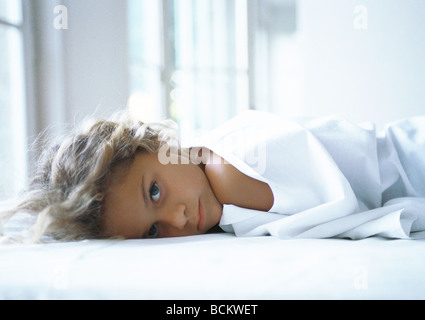 Mädchen im Bett liegend, Blick in die Kamera Stockfoto