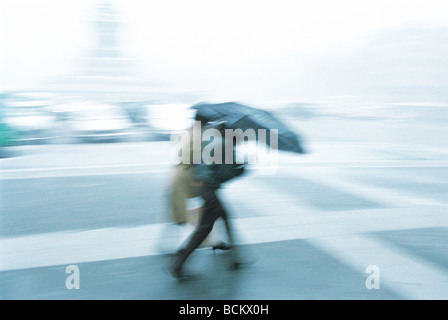 Menschen Kreuzung Straße im Regen, unscharf Stockfoto