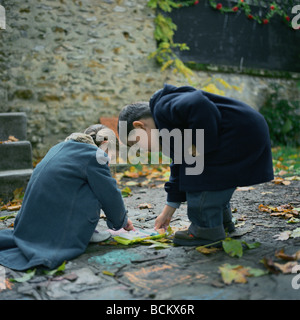 Jungen und Mädchen betrachten Kreiden auf Boden, im freien Stockfoto