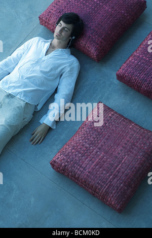 Mann auf Kissen, Kopf ruht, Kopfhörer, erhöhte Ansicht zuhört Stockfoto