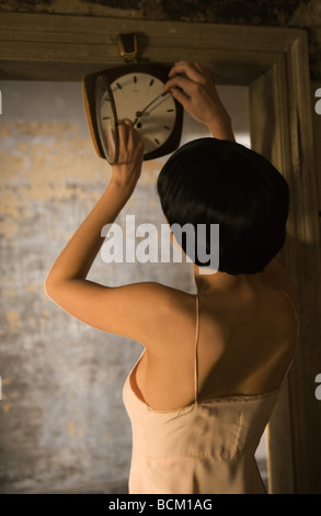 Anpassung der Frau die Hände auf Clock, Rückansicht, Taille bis Stockfoto