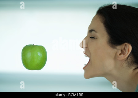 Apple, die schwebend in der Luft, Frau erreichen Sie mit offenem Mund, Augen geschlossen Stockfoto