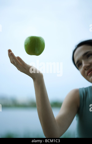 Apfel, schwebend in der Luft über zarte Frauenhand zugeschnitten Ansicht Stockfoto