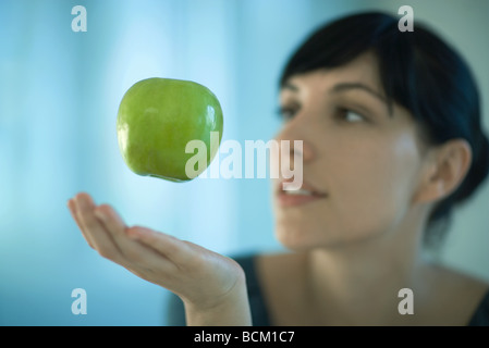 Apple, die schwebend in der Luft über zarte Frauenhand Stockfoto
