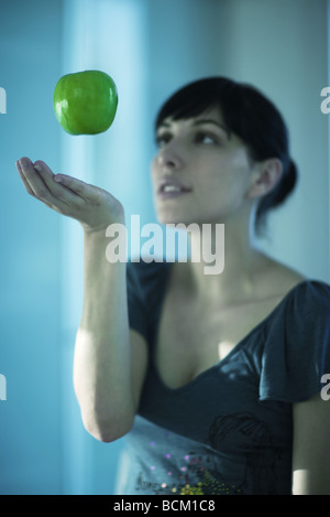 Apple, die schwebend in der Luft über zarte Frauenhand Stockfoto