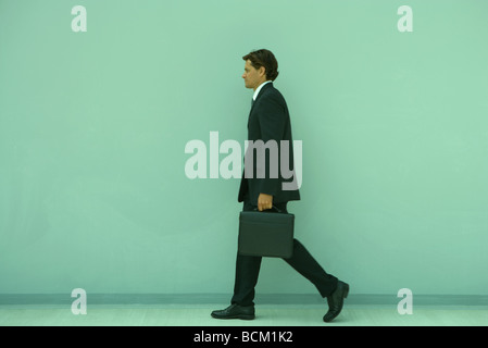 Geschäftsmann mit Aktenkoffer, Ganzkörperansicht, Seitenansicht Stockfoto