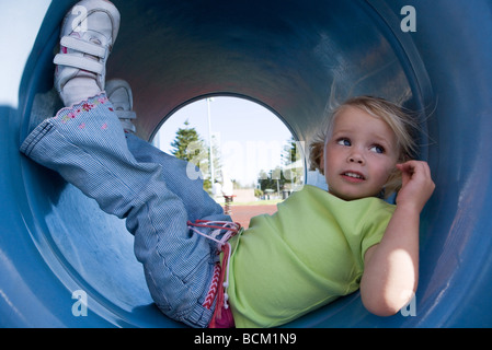 Mädchen liegend im Spielplatz-Tunnel mit Beine hoch, wegsehen, Nahaufnahme Stockfoto