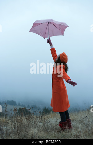 Teenager-Mädchen im Freien stehen, hält Regenschirm, Seitenansicht Stockfoto