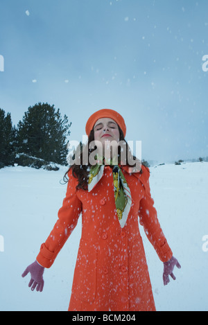 Teenager-Mädchen stehen im Schnee mit Kopf nach hinten, Augen geschlossen Stockfoto