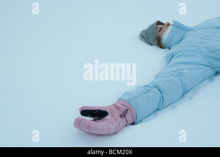 Preteen Mädchen im Schnee, gekleidet in Winterkleidung, liegend beschnitten Ansicht Stockfoto