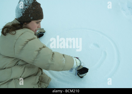 Teenager-Mädchen zeichnen Smiley-Gesicht im Schnee, Seitenansicht Stockfoto