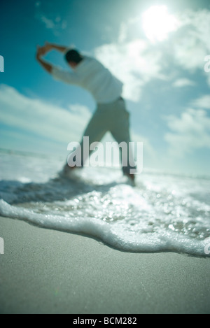 Mann am Strand mit erhobenen Armen, niedrige Winkel Rückansicht Stockfoto