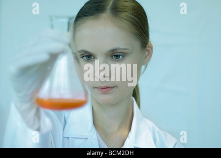 Wissenschaftlerin hält Becher mit Flüssigkeit im Inneren, blickte, Nahaufnahme Stockfoto