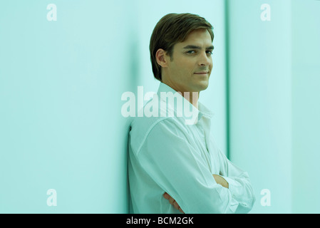 Mann mit verschränkten, Armen Wand gelehnt lächelnd in die Kamera Stockfoto