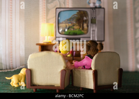 Kunststoff paar vor dem Fernseher im Wohnzimmer Miniatur, Rückansicht Stockfoto