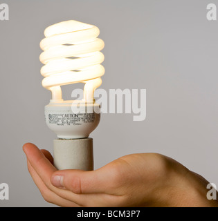 Hand, die eine neue Energie effiziente kompakte Leuchtstoff Glühbirne Stockfoto