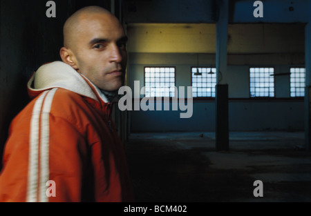 Junger Mann mit Jacke im Warehouse, Blick in die Kamera Stockfoto