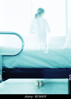 Patient im Krankenzimmer stehen, Blick aus Fenster, Sicht nach hinten Stockfoto