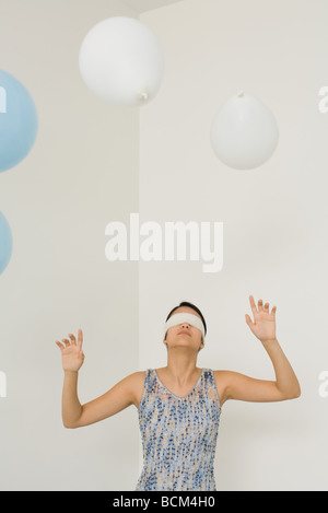 Frau mit verbundenen Augen, Hände hob, Ballons schweben über dem Kopf Stockfoto