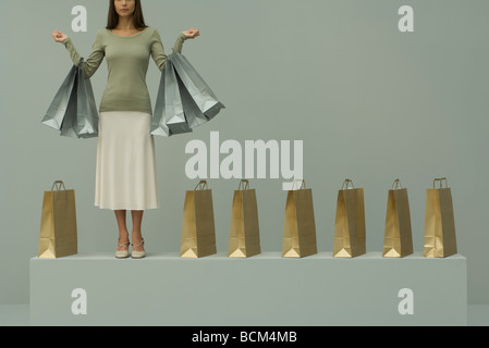 Frau hält mehrere Einkaufstaschen, mehr Taschen aufgereiht neben ihr beschnitten Ansicht Stockfoto