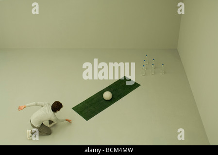 Bowling auf Spur von Kunstrasen mit Ball und Flaschen Wasser, erhöhte Ansicht Mann Stockfoto