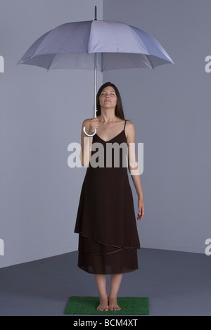 Weibliche stehend auf Kunstrasen, mit Regenschirm, schloss die Augen Stockfoto
