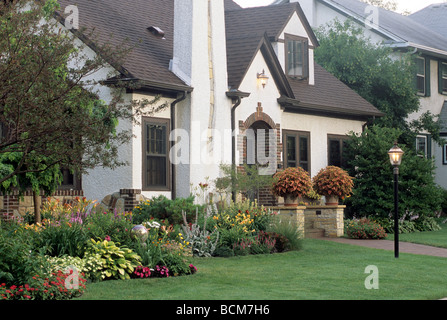 BUNTE SOMMERBLUMEN UND STAUDEN UND GROßE TÖPFE VON COLEUS ZIEREN DIE VORDERSEITE DIESES HAUS IN MINNEAPOLIS, MINNESOTA. MITTEN IM SOMMER. Stockfoto