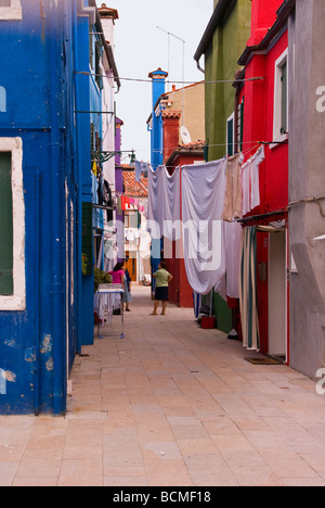 Italien Veneto Burano bunt bemalten Häusern auf schmalen Straße Nachbarn weibliche Nachbarn sprechen unter Wäsche aufhängen Stockfoto