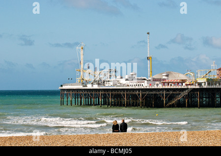 Zwei Personen sitzen auf der Kiesstrand in der Nähe von Brighton Pier in Sussex. Foto von Gordon Scammell Stockfoto