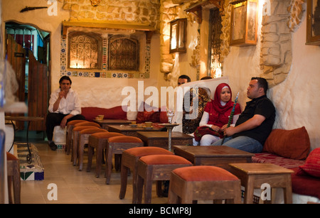 In der Medina von Tunis Paare ruhig sitzen, um als die Männer rauchen Tabak durch lange Glas-Wasserpfeifen genannt Chichas zu plaudern. Stockfoto