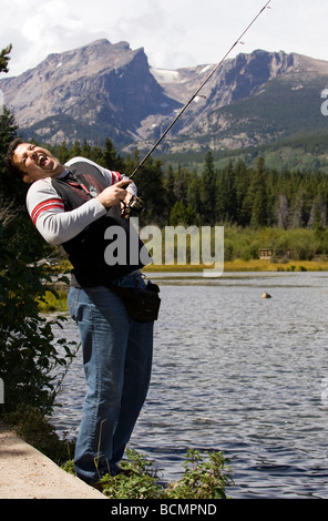 Junger Mann vorgibt, große Fische - Sprague Lake, Rocky Mountain National Park, in der Nähe von Estes Park, Colorado USA fangen Stockfoto