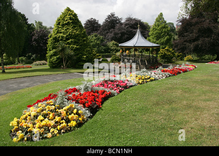 Stadt von Truro, England. Beete in voller Blüte in Truro Victoria Gardens mit dem viktorianischen Musikpavillon im Hintergrund. Stockfoto