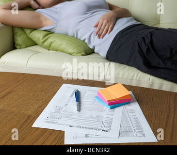 Steuerformulare auf dem Tisch liegende Frau auf Sofa im Hintergrund Stockfoto