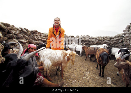 Lächelndes ethnischen Tajik Mädchen tendenziell Ziegen mit ihrer Großmutter Taxkorgan Tajik autonome Grafschaft, Kashgar Präfektur, Xinjiang Stockfoto