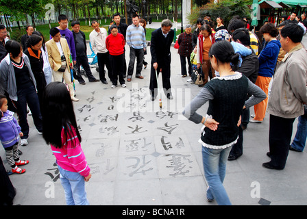 Elerly Chinesisch Mann praktizierender Kalligraphie auf dem Boden als Massen auf, Huanhua Park, Chengdu, Szechwan-Provinz, China Stockfoto