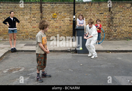 Kinder spielen Cricket in der Straße Junge und Mädchen. Brunswick Street Walthamstow London E17 mit dem Mülleimer im Wicket. 2009 HOMER SYKES Stockfoto