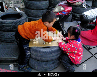 Kinder von Wanderarbeitnehmern chinesischen Schach in Schrottplatz, Shanghai, China Stockfoto