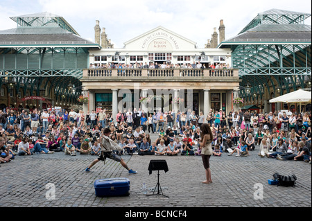 Eine Straße Entertainer führt zu einer großen Schar von Touristen in Covent Garden in London. Stockfoto