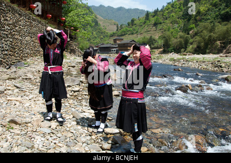 Drei lange Haare Yao Frauen Vorbereitung Haar neben Fluss Huangluo Dorf Guangxi China Stockfoto