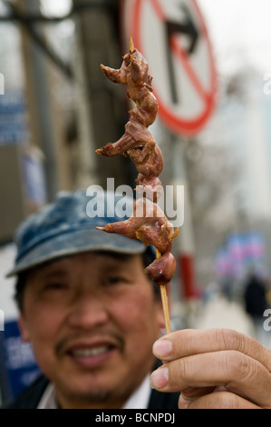 Ein Mann hält Küken am Spieß Stockfoto