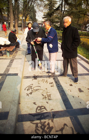 Ältere chinesische Männer üben mit großen Kalligraphie Tinte Bürste und Wasser auf dem Boden, Peking, China Stockfoto