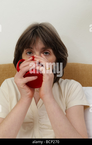 Frau im Bett heißes Getränk Tee Kaffee trinken Stockfoto
